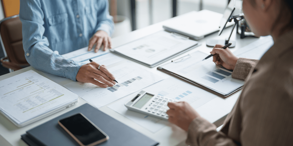 Two professionals analyzing reports and charts on a desk, highlighting strategies for online reputation management and SEO in response to Google's AI Overviews.